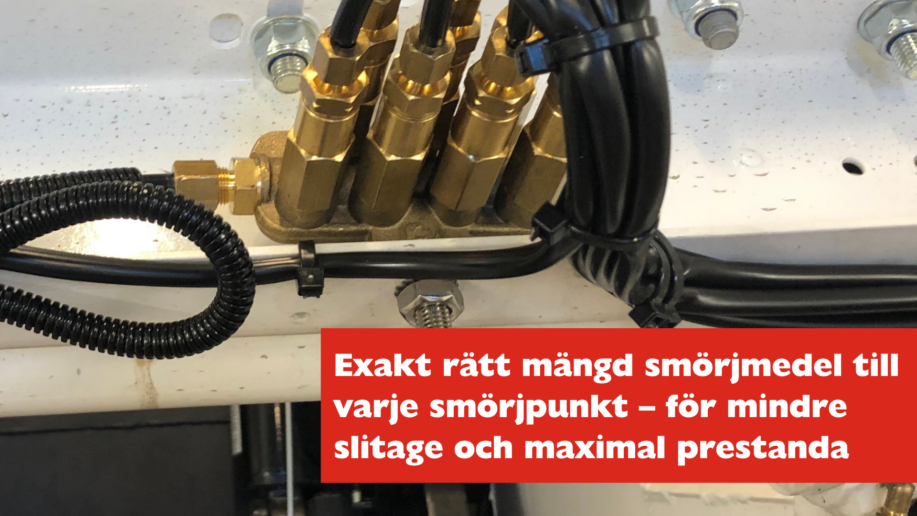 Närbild på fördelningsblock för centralsmörjning med flera smörjpunkter och slangar anslutna, tillsammans med texten: 'Exakt rätt mängd smörjmedel till varje smörjpunkt – för mindre slitage och maximal prestanda