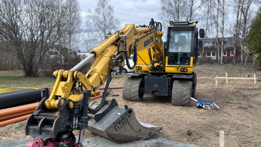 Grävmaskin med monterat iDig-system i fält, redo för arbete på ett mindre byggprojekt