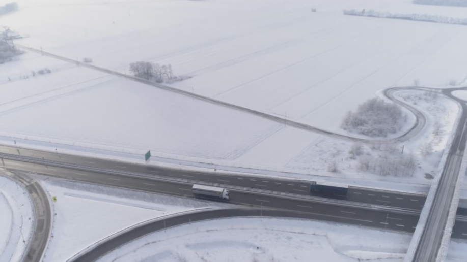 Vinterväg sedd uppifrån med lastbil i trafik, illustrerar behovet av säkert grepp och framkomlighet med automatiska snökedjor från Rotogrip.