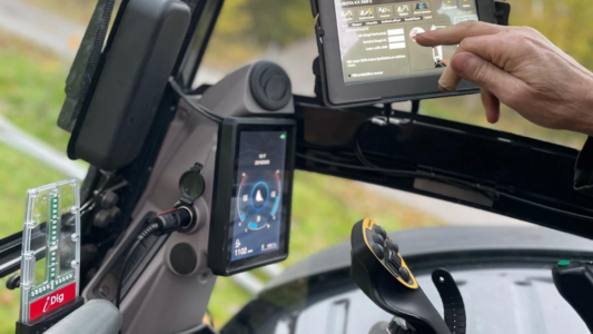 Förare i grävmaskin använder iDig grävsystem på display i hytten för att se djup och lutning i realtid.