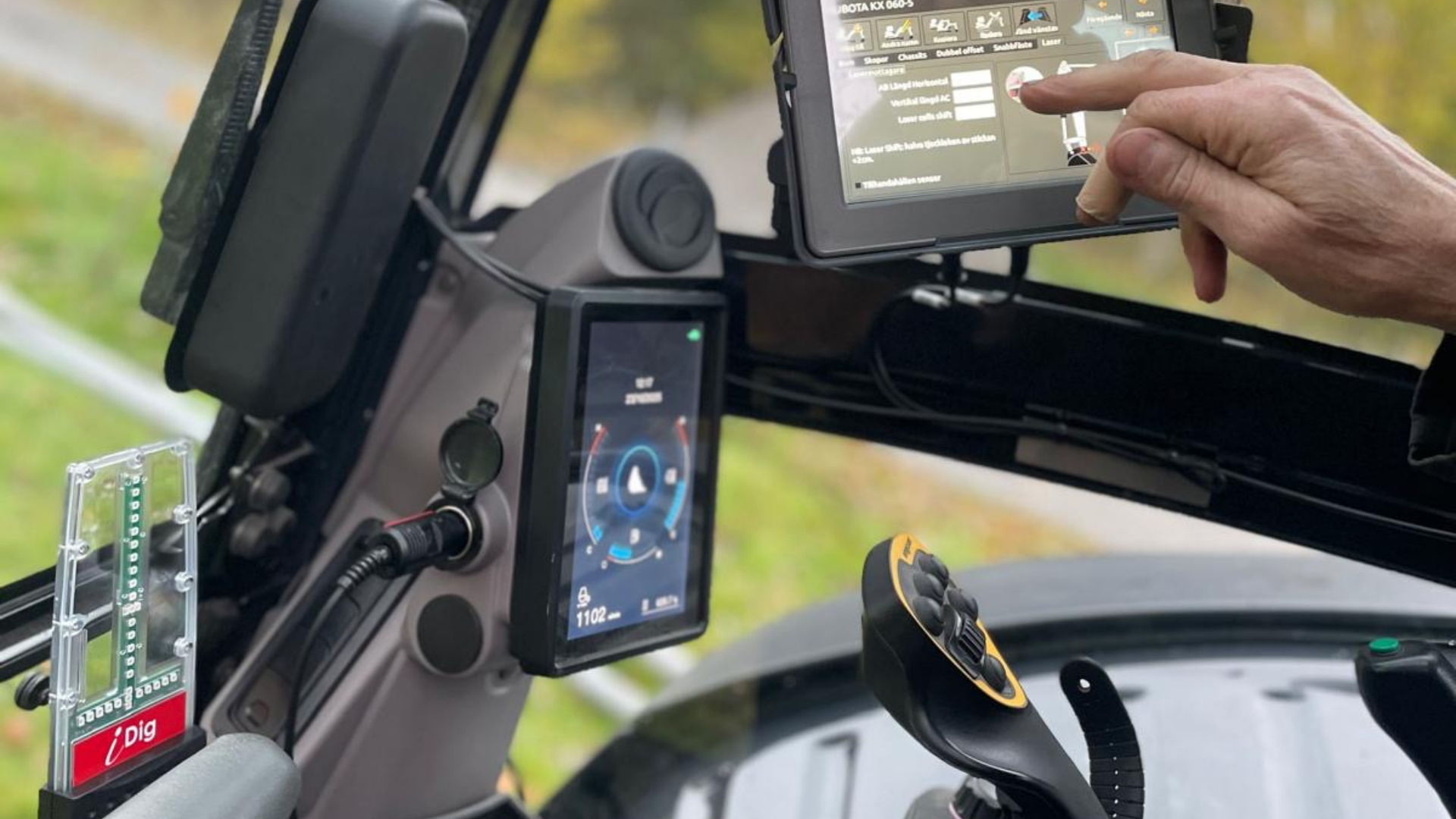 Förare i grävmaskin använder iDig grävsystem på display i hytten för att se djup och lutning i realtid.