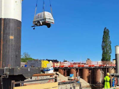 STS mobila AC-service-släp lyfts med kran ut till en pråm vid ett pålningsarbete i hamnmiljö
